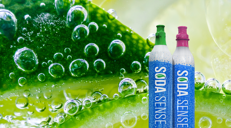 Two Soda Sense CO₂ canisters standing upright on a blue background. The canister on the left has a green cap labeled 